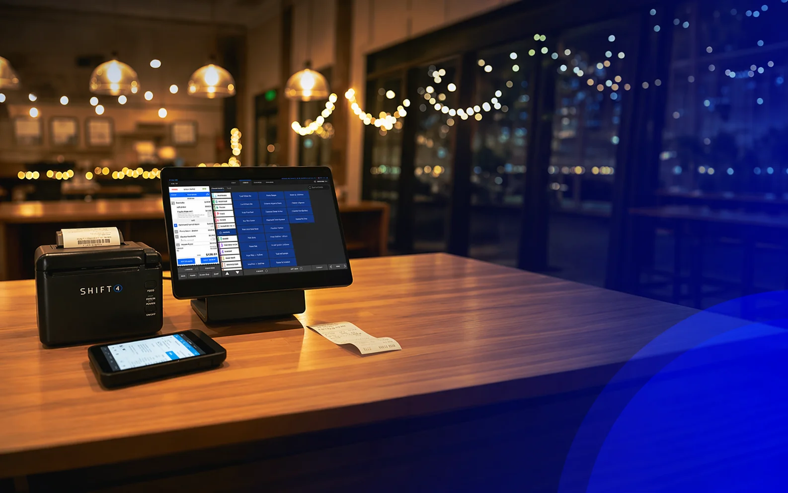 Shift4 Dine POS terminal, printer, and handheld on a restaurant table at night